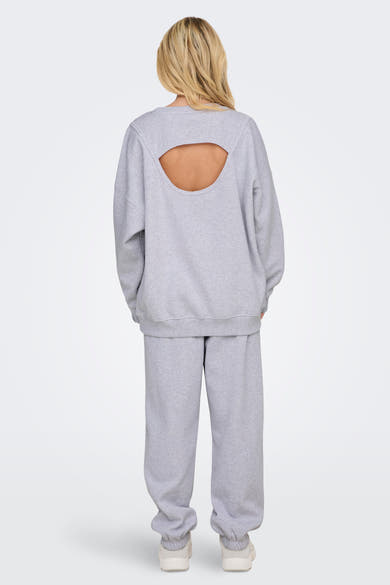 Sweat col rond gris de ONLY, avec une découpe dans le dos, porté avec un pantalon de survêtement assorti.