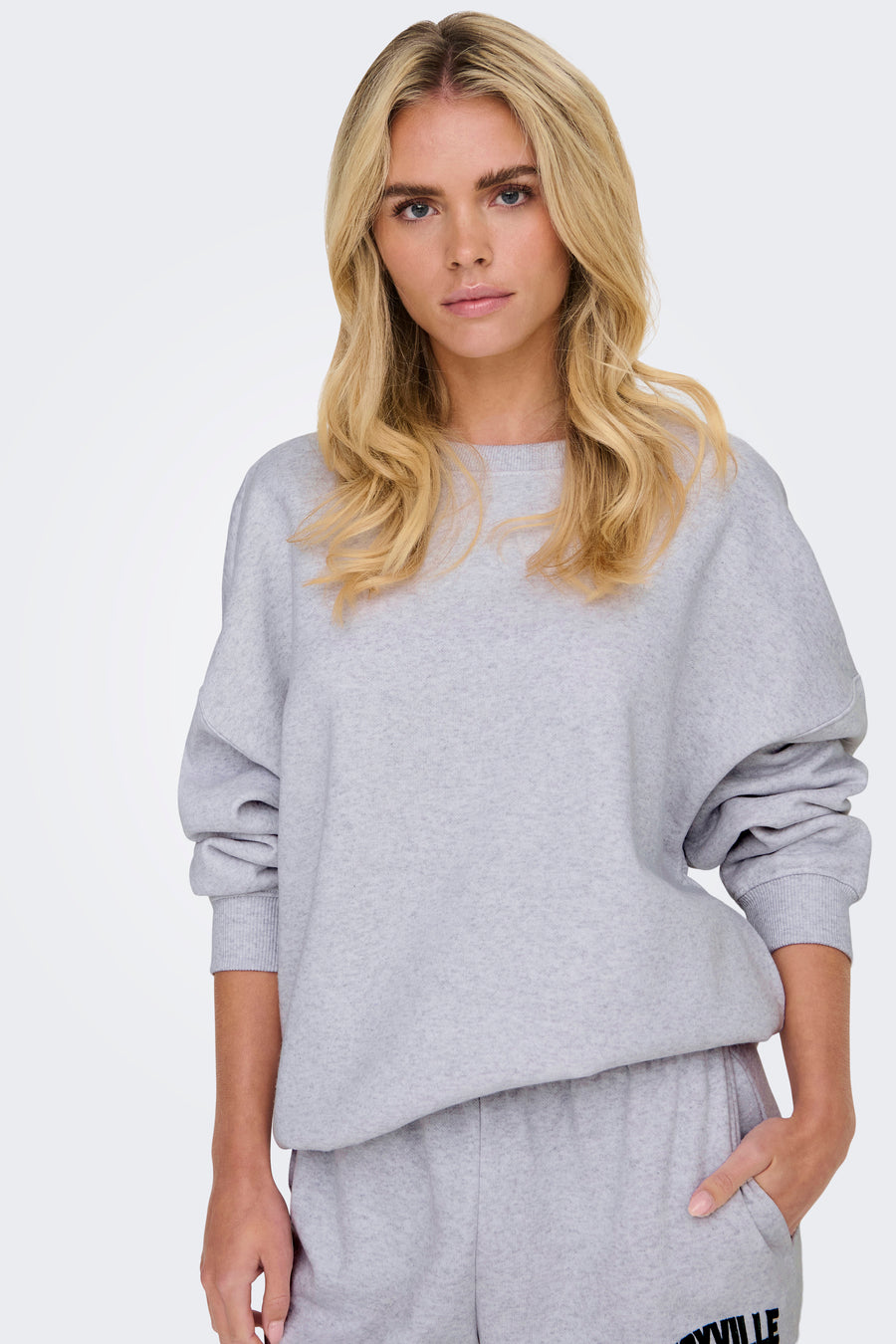 Sweat à col rond gris de ONLY, porté par un mannequin aux cheveux blonds ondulés.