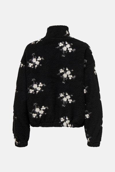 Polaire noire de ONLY, avec motif floral brodé blanc sur toute la surface.
