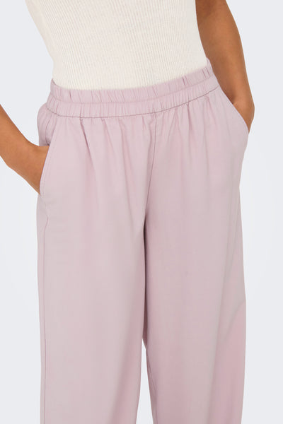 Pantalon rose ONLY®, coupe ample avec poches et taille élastique, porté avec un haut en maille côtelée.
