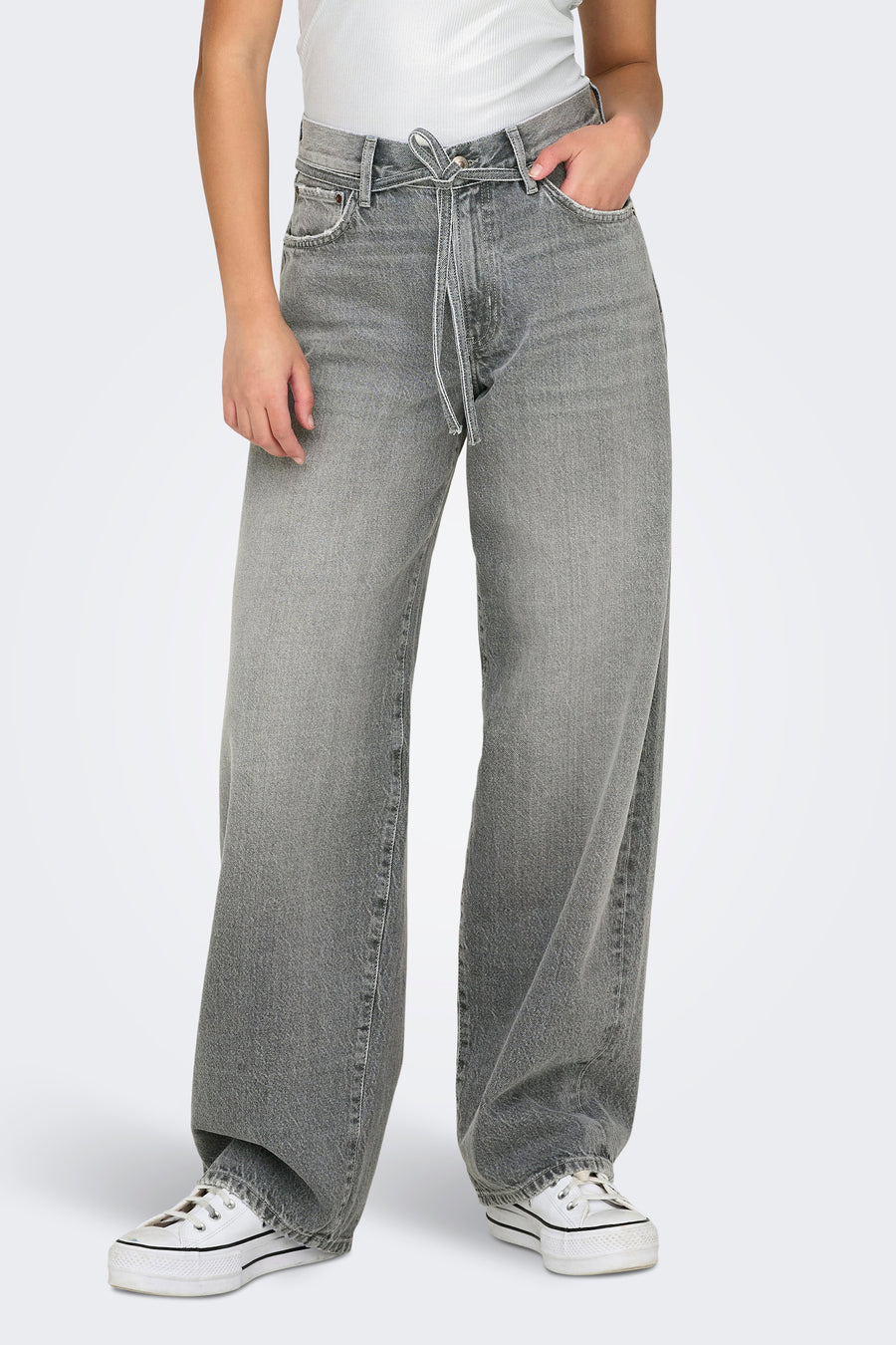 Jean droit en denim gris moyen de ONLY, avec une ceinture à nouer, porté avec un top blanc et des baskets blanches.
