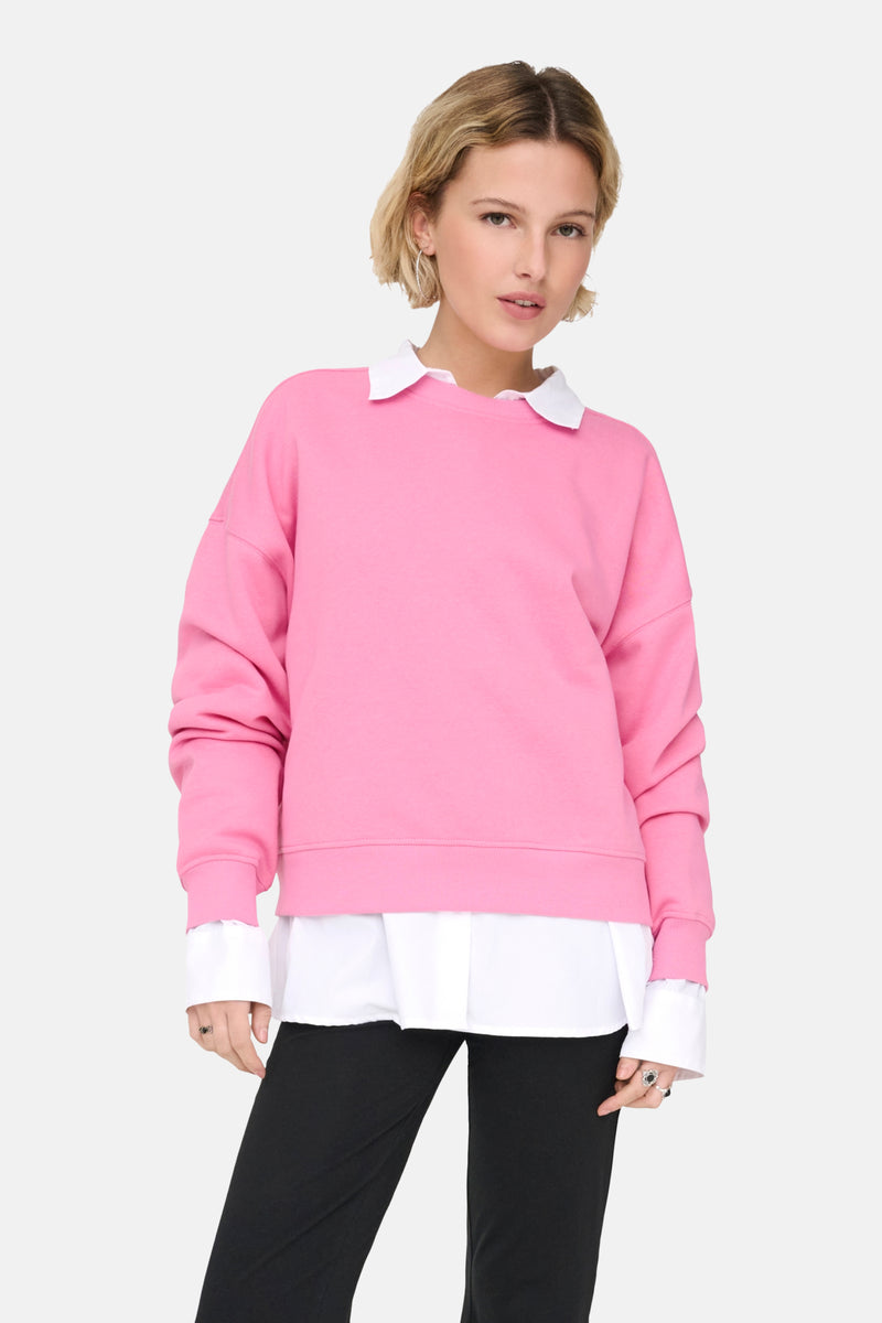 Sweatshirt van ONLY®, gedragen met een wit overhemd met kraag en een zwarte broek.