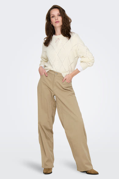 Pull à col rond écru de ONLY, avec motif losanges ajouré, porté avec un pantalon beige ample.
