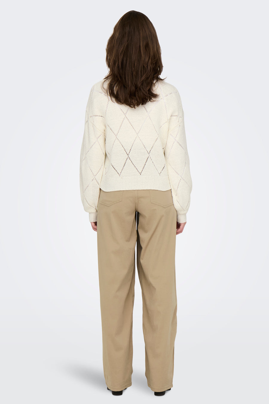 Pull à col rond écru de ONLY, avec motif en losanges et manches longues, porté avec un pantalon beige.
