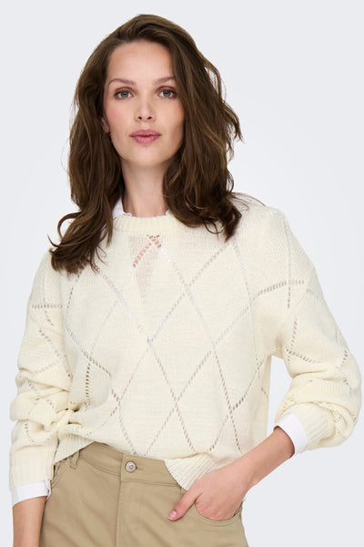 Ecru ronde hals trui van ONLY, met ruitpatroon met ajoursteken, gedragen over een wit overhemd en een beige broek.