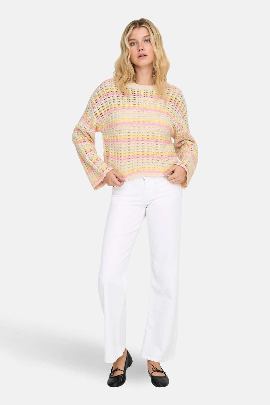 Pull à col rond multicolore de ONLY, à rayures roses et jaunes, porté avec un pantalon blanc et des ballerines noires.
