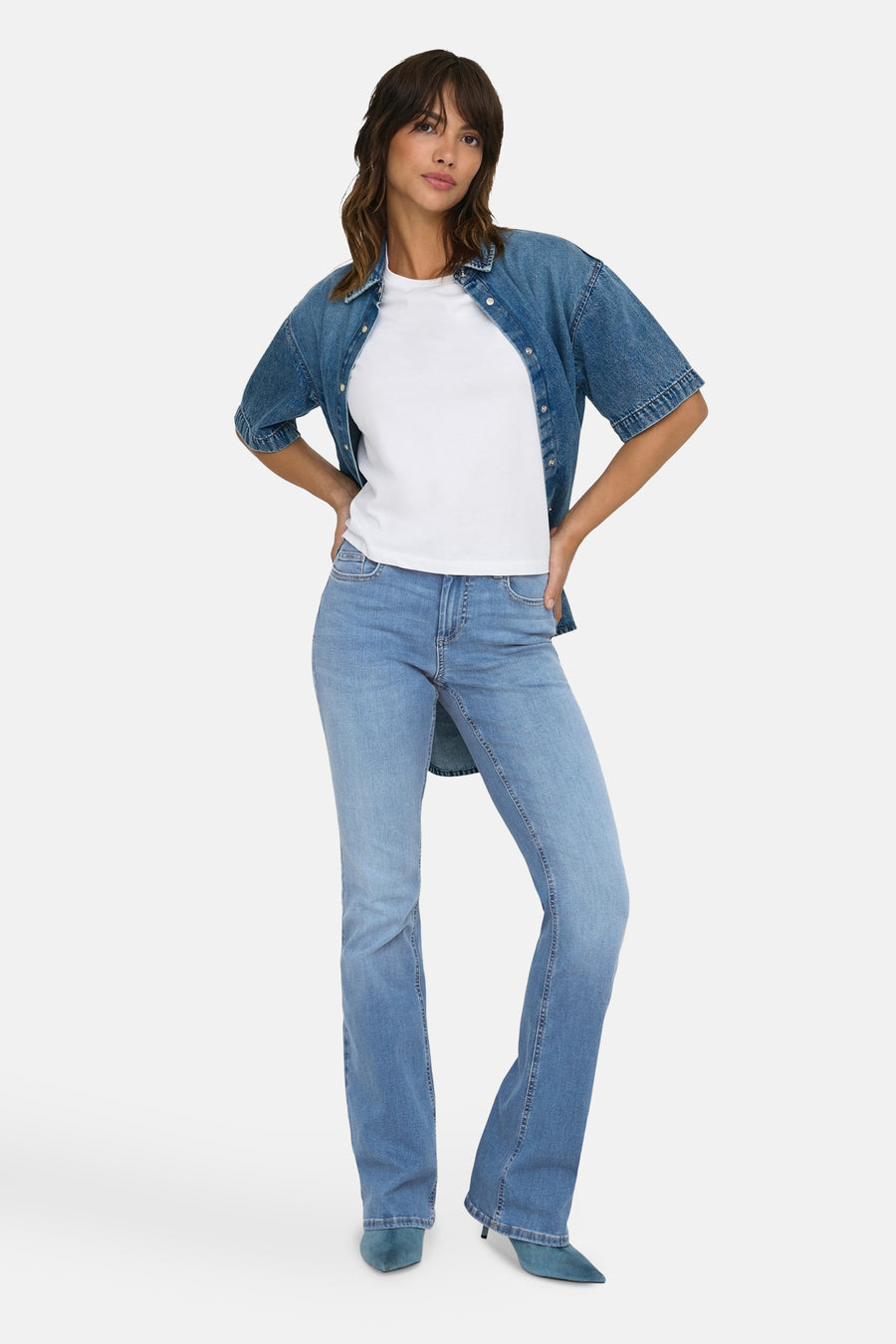 Jean évasé bleu moyen de ONLY, porté avec un t-shirt blanc et une chemise en jean.