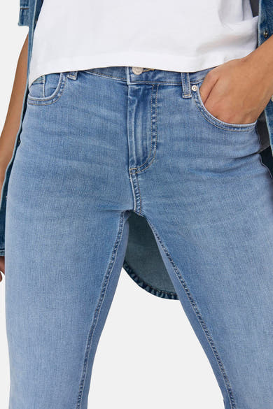 Jean évasé bleu moyen de ONLY, avec une main dans la poche et une veste en jean visible.
