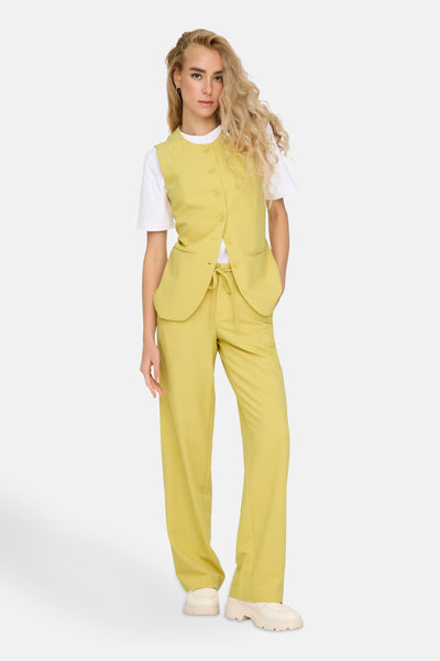 Pantalon de costume jaune de ONLY®, porté avec un t-shirt blanc et un gilet boutonné assorti.