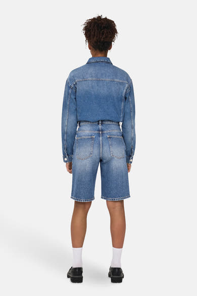 Short bleu denim, de ONLY®, porté avec une veste en jean assortie, des chaussettes blanches et des chaussures noires.