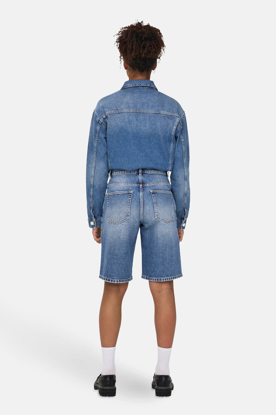 Short bleu denim, de ONLY®, porté avec une veste en jean assortie, des chaussettes blanches et des chaussures noires.