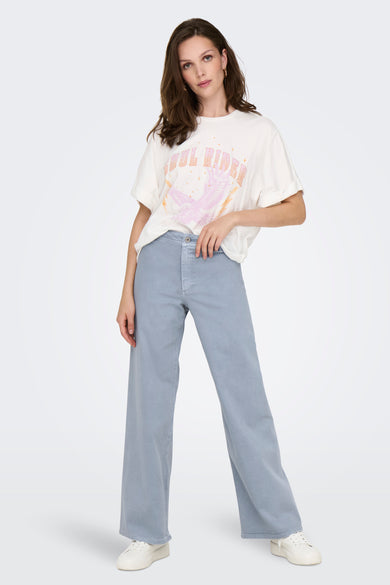 Pantalon coloré bleu clair de JDY, coupe ample et jambes larges, porté avec un t-shirt imprimé et des baskets blanches.
