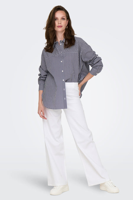 Gekleurde witte denim broek van JDY, gedragen met een marineblauw en wit gestreept overhemd en witte sneakers.