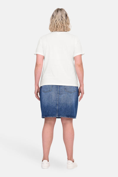 Wit T-shirt met korte mouwen van CARMAKOMA, gedragen met een blauwe spijkerrok en witte sneakers.