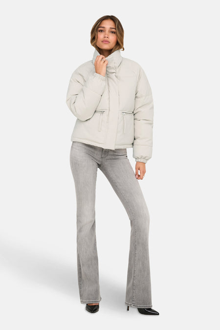 Korte beige jas van JDY, met ritszakken, gedragen met een grijze flared jeans en zwarte pumps.