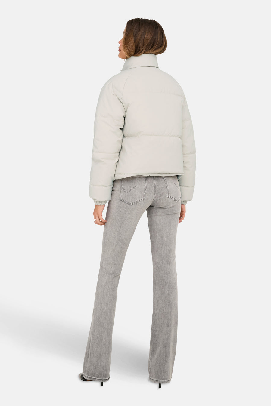 Veste courte beige de JDY, vue de dos, portée avec un jean gris évasé et des talons aiguilles.