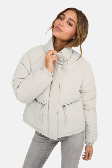 Veste courte beige de JDY avec poches zippées et manches longues, portée avec un jean gris.
