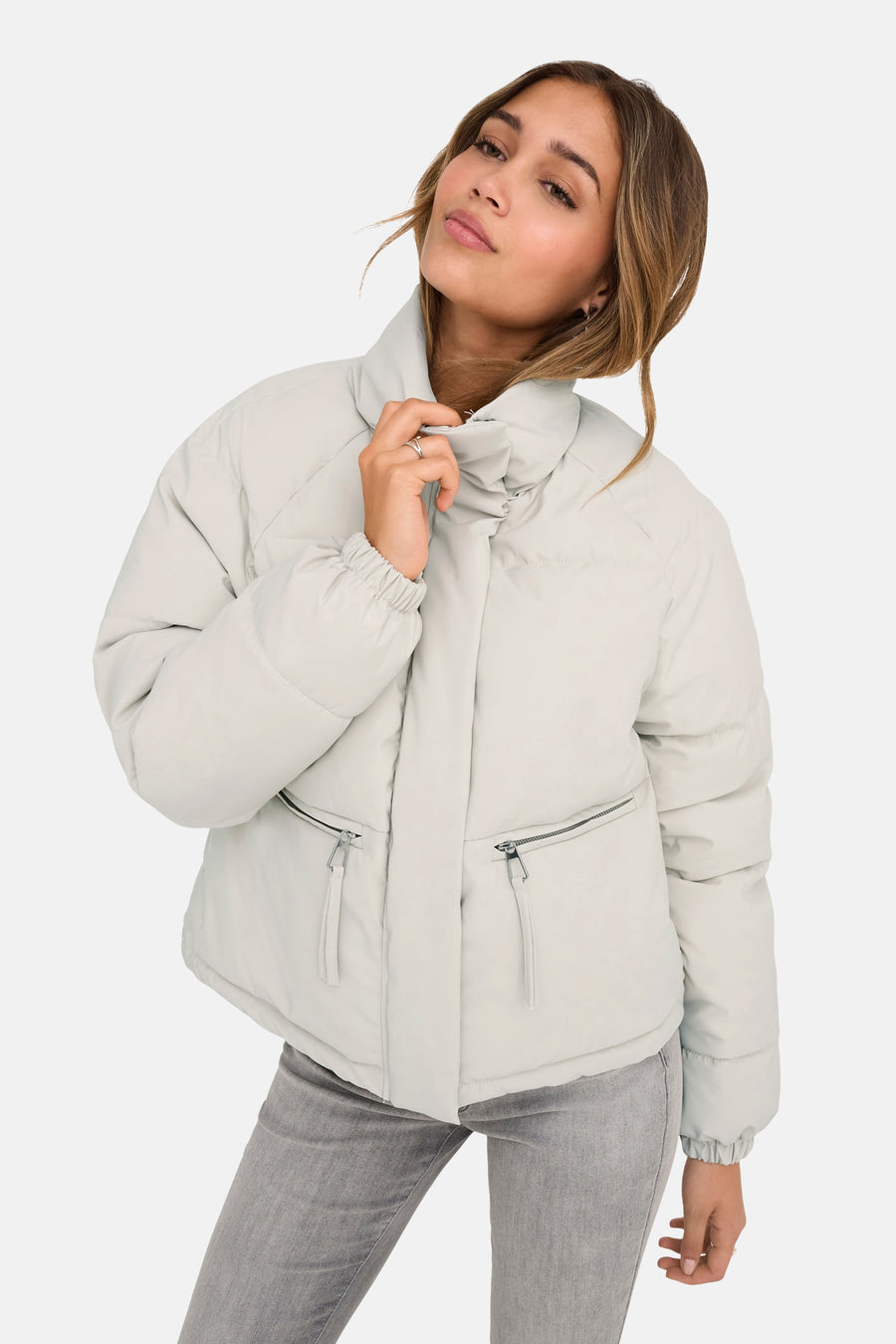 Veste courte beige de JDY avec poches zippées et manches longues, portée avec un jean gris.

