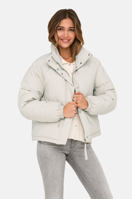 Korte beige jas van JDY, met opstaande kraag en ritssluiting, gedragen met een grijze jeans.