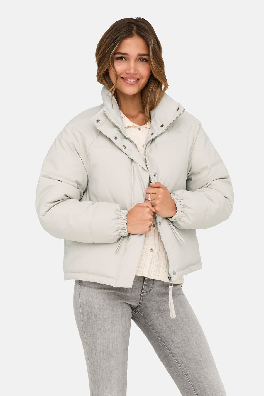 Veste courte beige de JDY, avec col montant et fermeture éclair, portée avec un jean gris.

