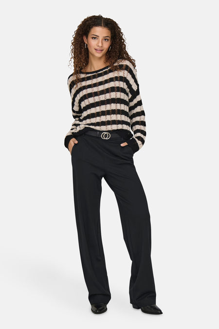 Pantalon noir de ONLY®, porté avec une ceinture noire à boucle dorée et un pull rayé.