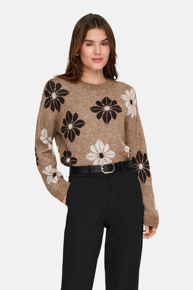 Pull à col rond beige de ONLY®, à motif floral blanc et marron, porté avec un pantalon noir et une ceinture.