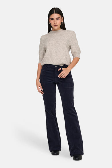 Pull col rond gris de JDY, agrémenté de perles décoratives, porté avec un pantalon en velours côtelé.