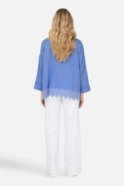 Chemisier bleu décontracté de ONLY®, avec ourlet en dentelle et porté avec un pantalon blanc.