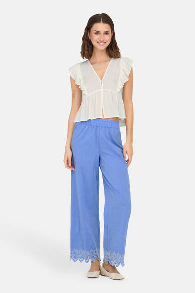 Blauwe broek van ONLY®, wijd met uitgesneden details aan de zoom, gedragen met een witte top en beige ballerina's.