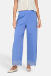 Blauwe broek van ONLY, met geborduurde kanten rand aan de enkels, gedragen met een witte top.