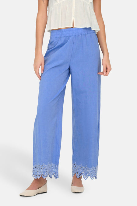 Blauwe broek van ONLY, met geborduurde kanten rand aan de enkels, gedragen met een witte top.