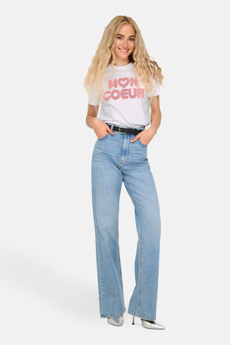 Wit T-shirt met korte mouwen van ONLY, gedragen met een high-waisted jeans en zilveren schoenen.