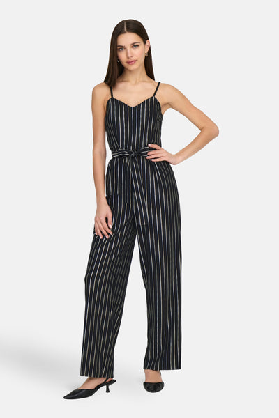 Combinaison noire rayée de ONLY®, avec ceinture nouée et bretelles fines, portée avec des escarpins noirs.
