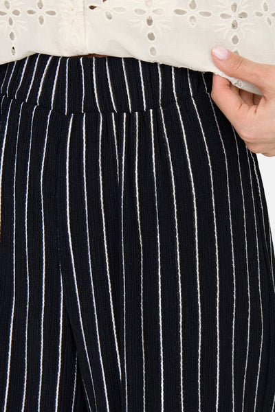Pantalon noir à rayures verticales blanches par ONLY, détail du haut en dentelle blanche.
