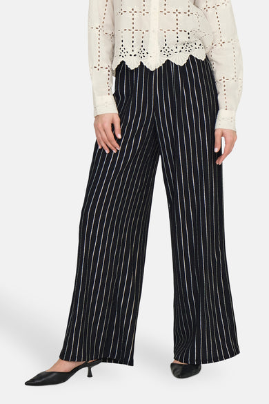 Zwarte gestreepte broek van ONLY, gedragen met een doorzichtig wit blouse en zwarte puntlakken.
