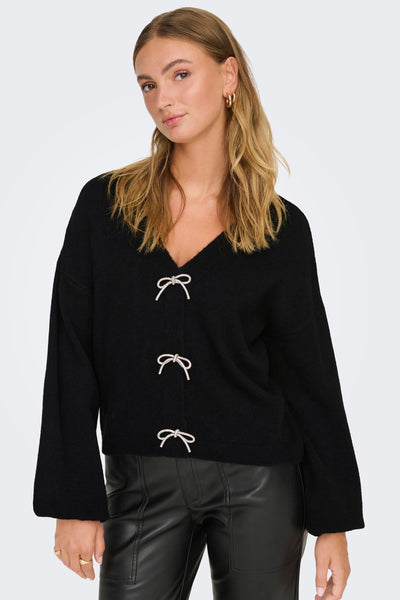 Zwarte gebreide cardigan van ONLY®, versierd met decoratieve strikken, gedragen met een leren broek.