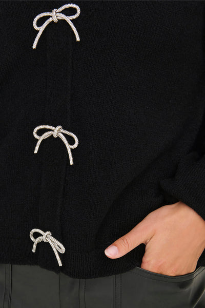 Zwarte cardigan van ONLY, versierd met glinsterende decoratieve strikken aan de voorkant, gedragen met een leren broek.