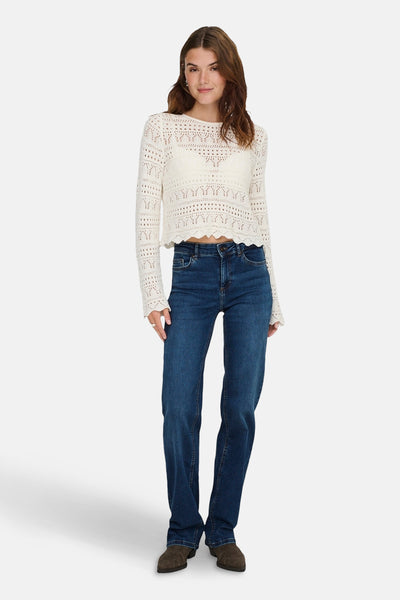 Donkerblauwe straight jeans van ONLY, gedragen met een gebroken witte gehaakte trui en bruine schoenen.