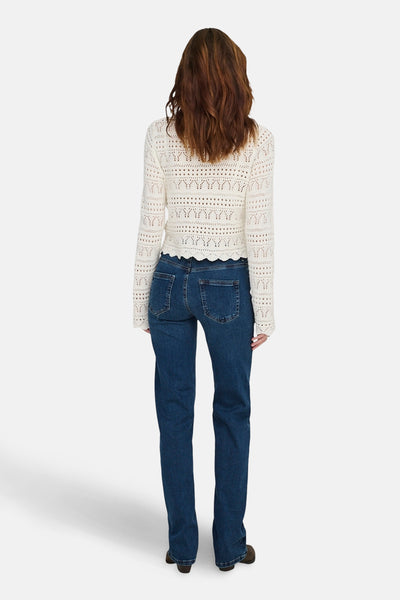 Jean droit en denim bleu foncé de ONLY, avec des poches arrières et porté avec un haut en maille ajourée blanc.