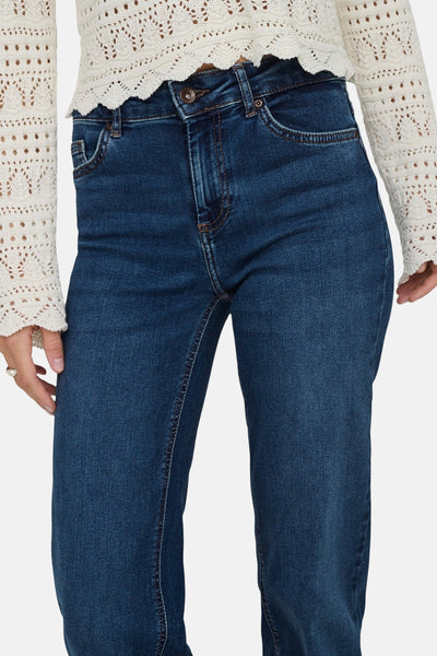 Jean droit bleu foncé de ONLY, porté avec un haut en maille crochetée beige.
