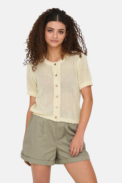 Ecru gebreid vest met open structuur van ONLY, met gouden knopen en gedragen met een kaki short.