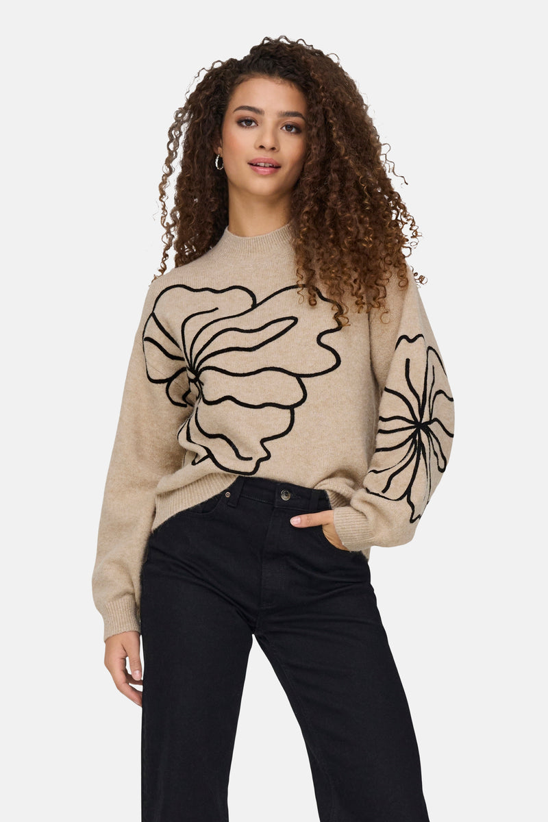 Beige ronde hals trui van JDY met zwart bloemenpatroon, gedragen met een zwarte jeans.