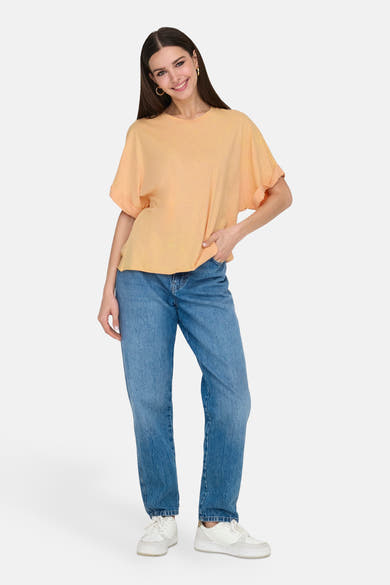 Oranje T-shirt met korte mouwen van ONLY, gedragen met een blauwe jeans en witte sneakers.