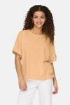 Oranje T-shirt met korte mouwen van ONLY, met een kleine decoratieve patch en gedragen met een witte broek.