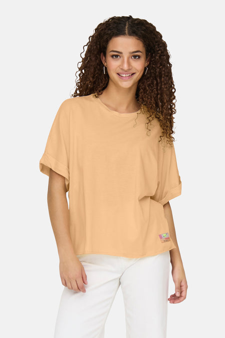 Oranje T-shirt met korte mouwen van ONLY, met een kleine decoratieve patch en gedragen met een witte broek.