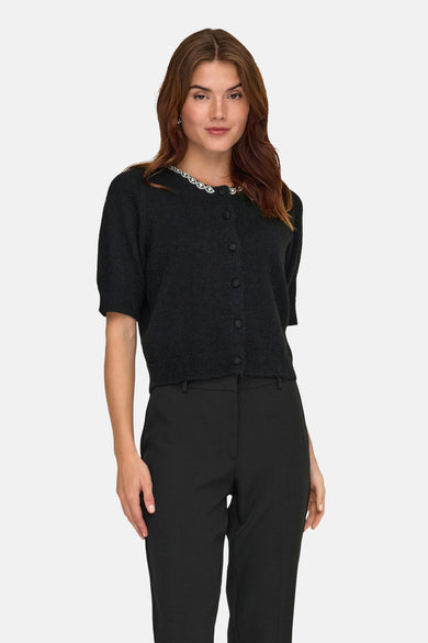 Zwarte gebreide bodywarmer van JDY met een halslijn versierd met strass-steentjes, gedragen met een klassieke zwarte broek.