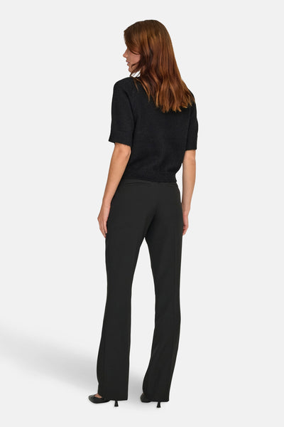 Zwarte bodywarmer van JDY, gedragen met een zwarte high-waist flared broek en zwarte pumps.