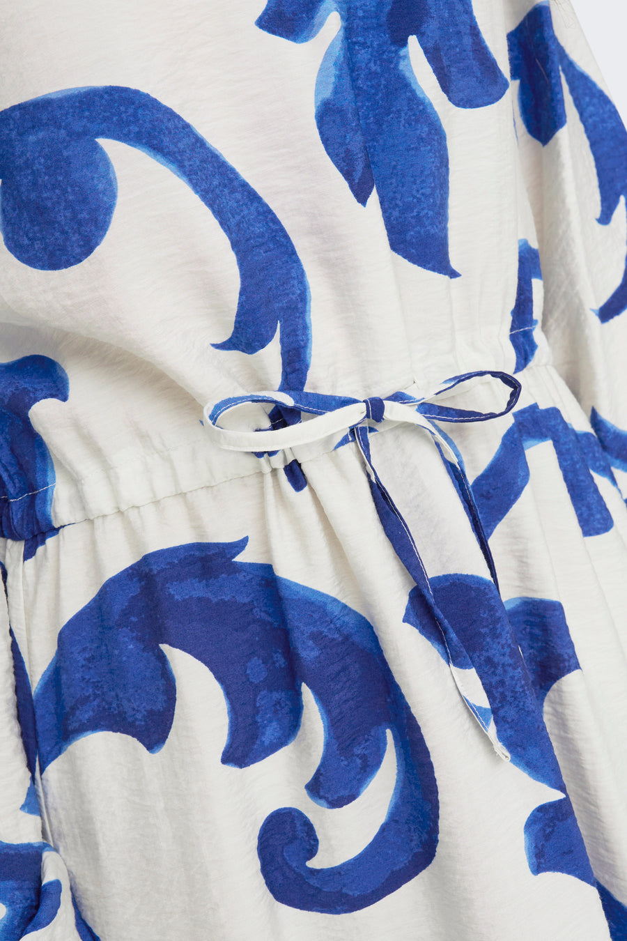 Blauwe jurk met lange mouwen van JDY, blauw-wit bloemenpatroon, met een strikceintuur in de taille.