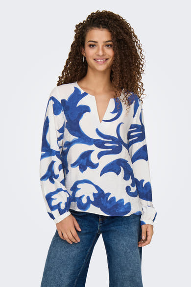 Blouse à manches longues bleue de JDY, avec un motif floral et un col en V, portée avec un jean.
