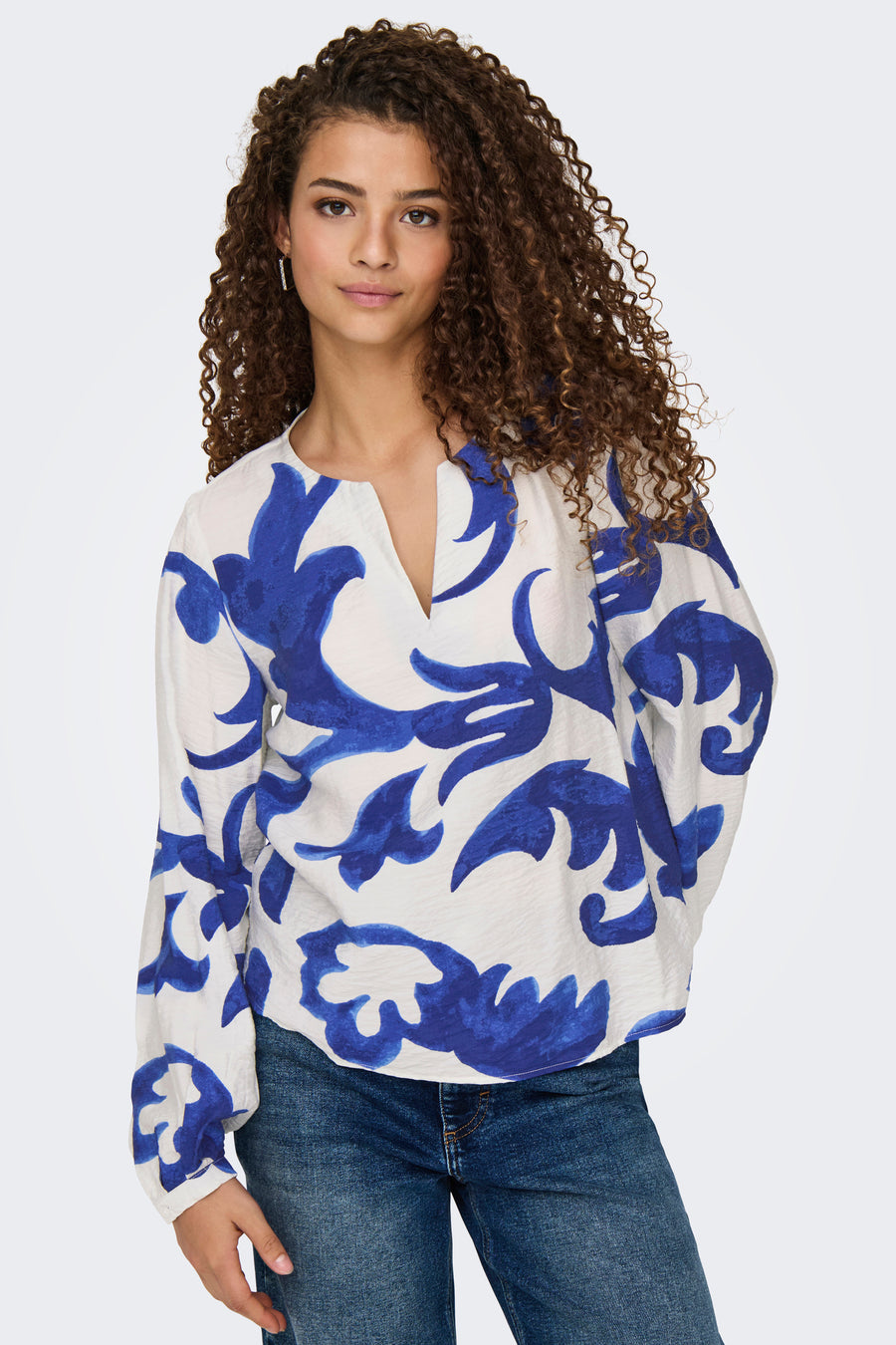 Blouse met lange mouwen van JDY in het blauw, bloemenprint op een witte achtergrond, gedragen met een spijkerbroek.